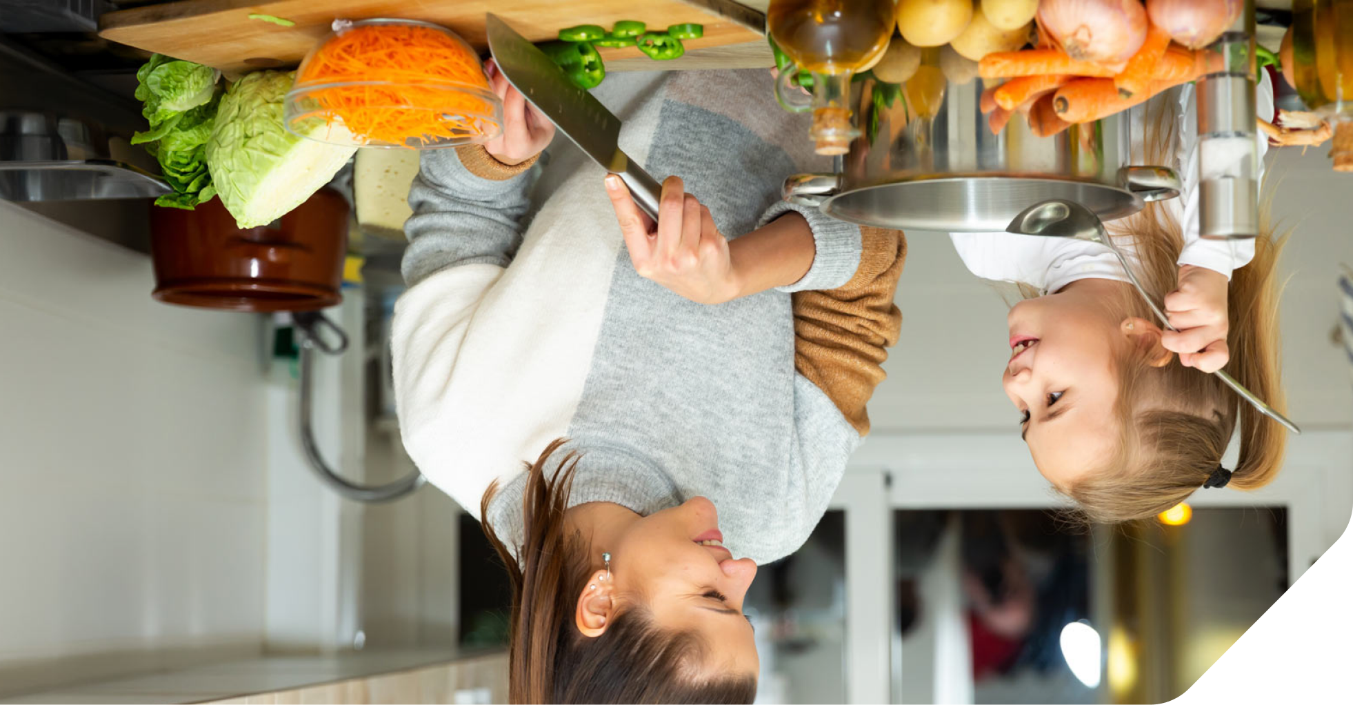 A young mother and child in their kitchen eating healthy vegetables.