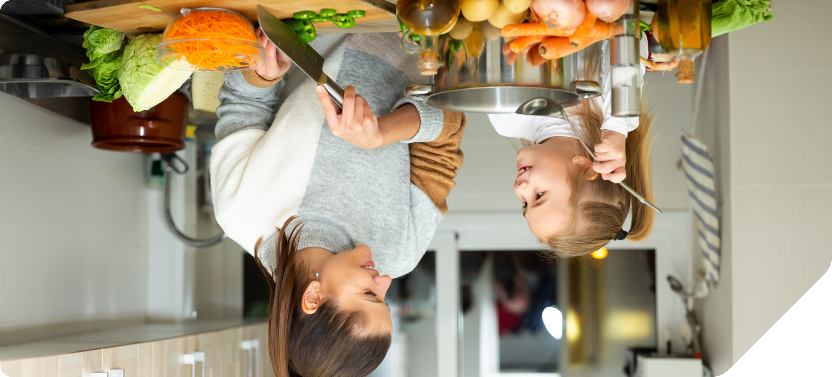 A young mother and child in their kitchen eating healthy vegetables.