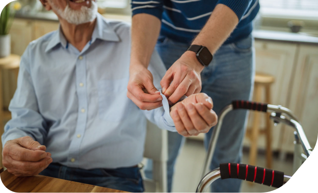 Helping an elderly man with a button on their shirt